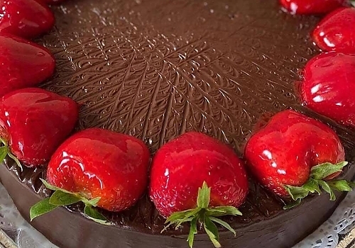 A cake with strawberries and chocolate on it showcasing mango tres leches. 